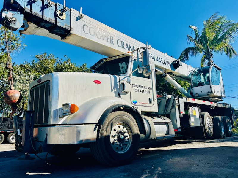 A branded Cooper Crane Peterbilt boom truck working a Southeast Florida job site