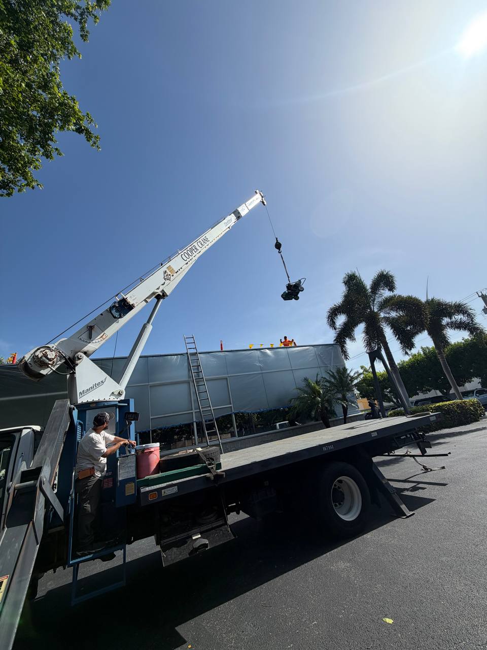 Cooper Crane boom truck hoisting roofing material onto a commercial roof